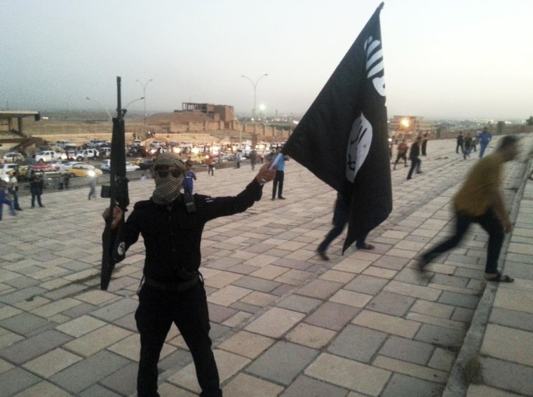 Image: A fighter of the ISIS holds a flag and a weapon on a street in Mosul