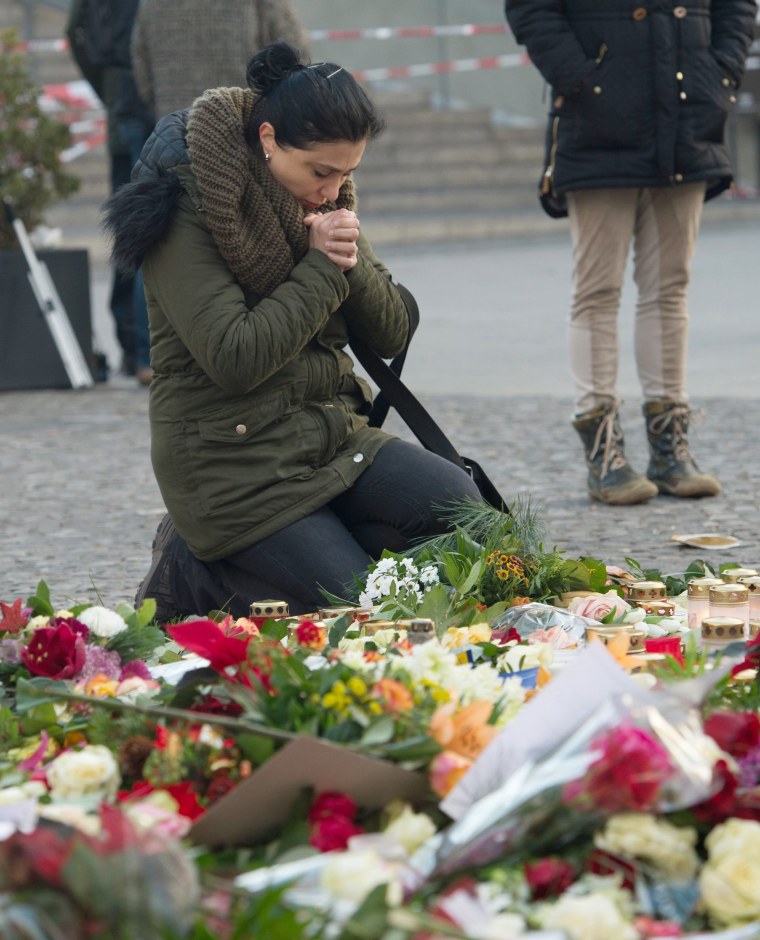 Image: A woman kneels near the site of the attack at the Christmas market 