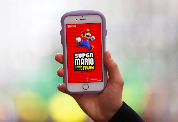 Image: A person poses to display Nintendo's \"Super Mario Run\" game on a mobile phone in Tokyo, Japan