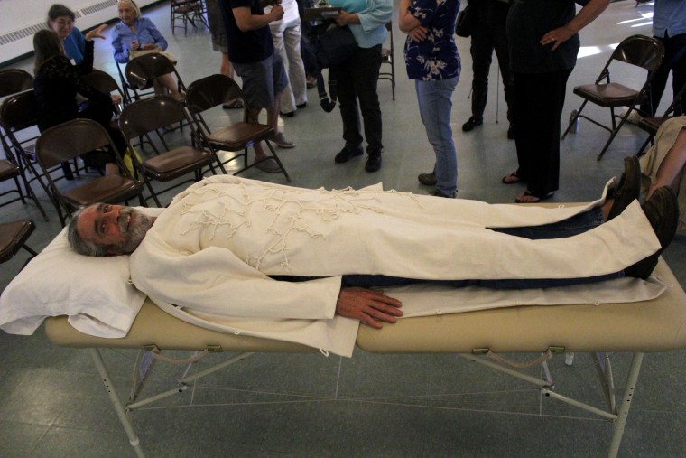 Dennis White tests his Infinity Suit, a hand-sewn shroud made of mushroom spores and other microorganisms that are supposed to aid in decomposition and neutralize toxins.