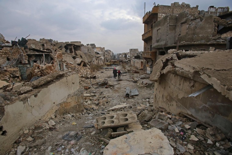 Image: Syrians walks down a destroyed street in Aleppo's al-Akroub neighbourhood on Dec. 17.