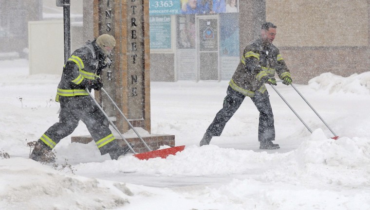 Mandan firefighters Shane Weltikol, left, and Chad Nicklos clear accumulating snow from outside the firehouse in downtown Mandan, N.D., as the Christmas Day blizzard intensifies on Sunday, Dec. 25, 2016.