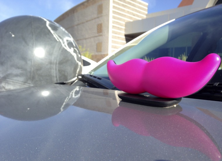 The signature pink mustache of ride-booking company Lyft sits on the hood of a vehicle during a news conference in Albuquerque, N.M., on Thursday, Aug. 18, 2016. Legislation signed earlier this year cleared up regulatory uncertainty and allowed for Lyft and other ride-booking services, like Uber, to resume operations in the state. (AP Photo/Susan Montoya Bryan)