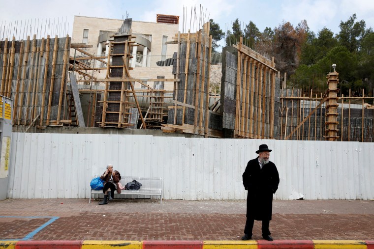 Image: Israelis are seen near a construction site in the Israeli settlement of Ramat Shlomo, in the occupied West Bank