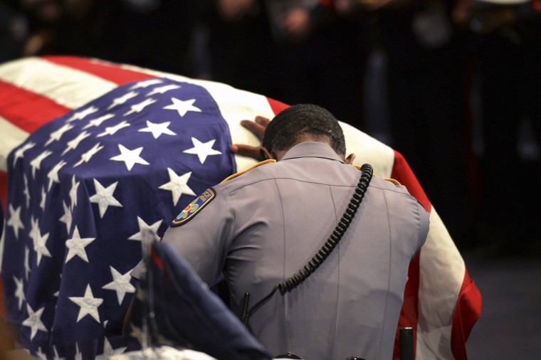Image: A member of Baton Rouge police Cpl. Montrell Jackson's unit kneels and touches his casket
