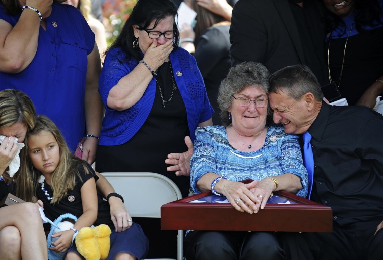 Image: Parents of East Baton Rouge Sheriff deputy Brad Garafola weep after being presented with a flag