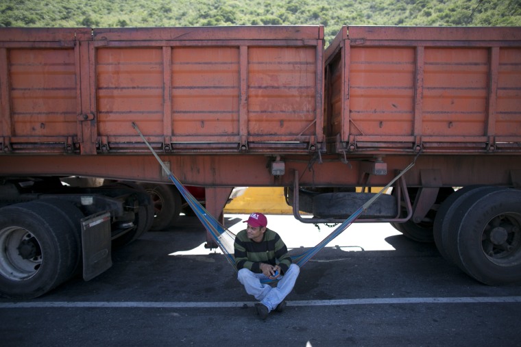 In this Nov. 14, 2016 photo, a truck driver rests on his hammock under his truck as he waits to enter the port in Puerto Cabello, Venezuela.