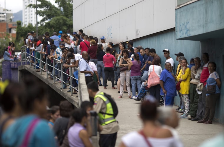 In this Nov. 18, 2016 photo, people wait outside a supermarket to buy government subsided food in Caracas, Venezuela.