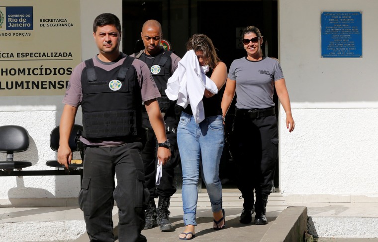 Image: Francoise Souza Oliveira, 40, wife of Greek Ambassador for Brazil Kyriakos Amiridis, is escorted by police officers