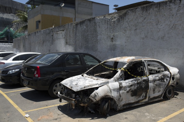 Image: A burned car sits in the parking lot of the police station in Belford Roxo, Brazil