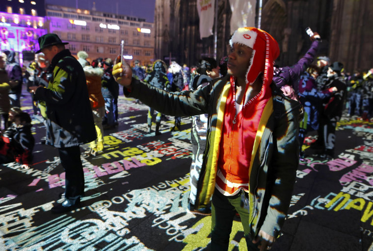 Image: A refugee Joseph from Kenia takes a selfie during the laser installation \"Time Drifts Cologne\" before New Year celebrations for 2017 in Cologne