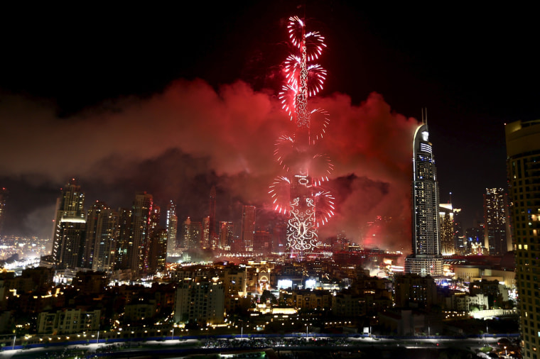 Image: The Address Downtown Dubai hotel and residential block is seen engulfed by fire as fireworks explode over the Burj Khalifa, the tallest building in the world, during the New Year celebrations