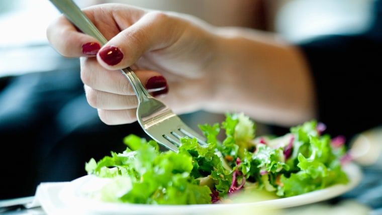 Close-up of woman's hand eating salad
