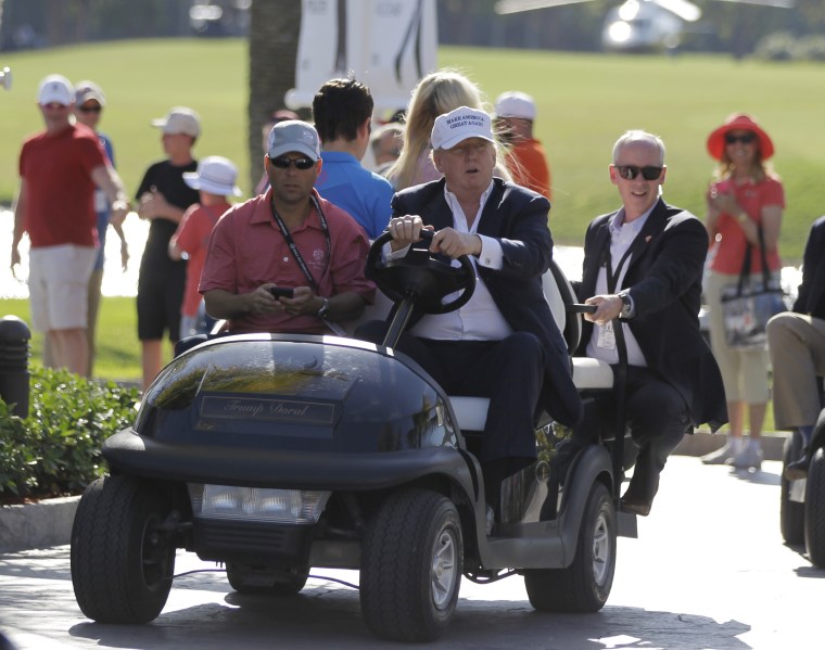 Image: Then-Republican presidential candidate Donald Trump drives himself around the golf course