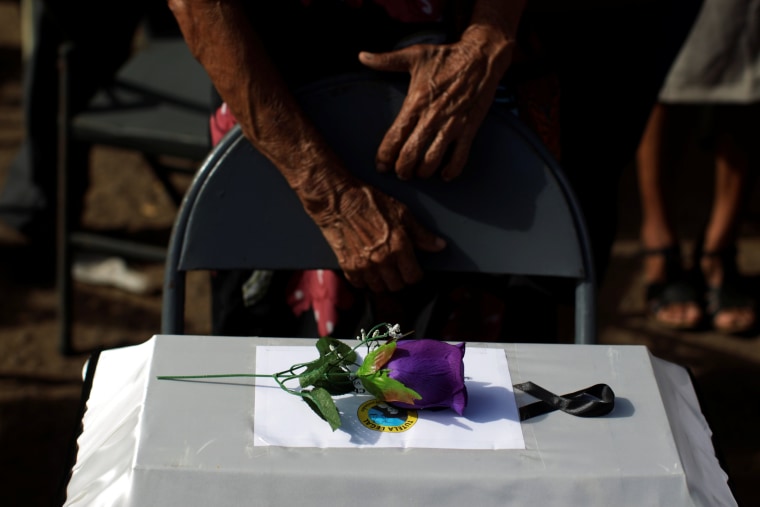 People observe the remains of their relatives as they participate in a ceremony to commemorate the 35th anniversary of the El Mozote massacre in El Mozote