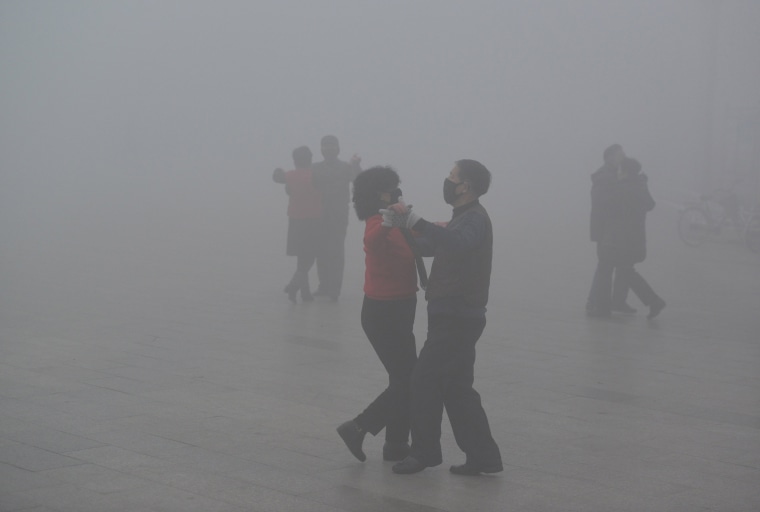 Image: People wearing masks dance at a square among heavy smog during a polluted day in Fuyang