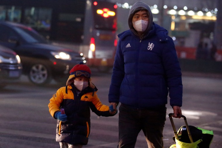 Image: People wear face masks as they cross a street on a polluted day in Beijing