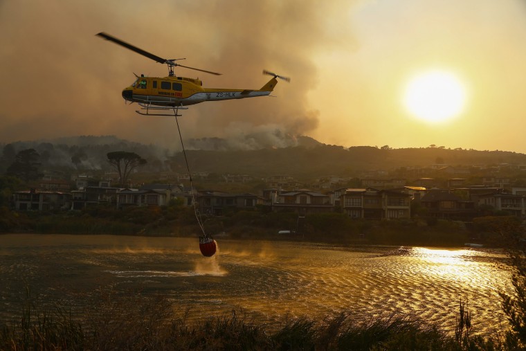 Image: Firefighting helicopters battle a vegetation fire fanned by gale force winds raging in the Helderberg mountains around Somerset West, South Africa on Jan. 4.