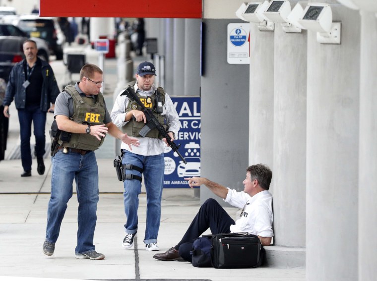 Image: Law enforcement officers talk to a man at Fort Lauderdale-Hollywood International Airport after the deadly shooting.