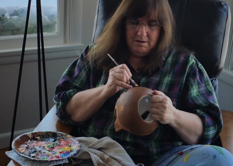 Strawn, 60, paints baby helmets from the living room of her Washington home.