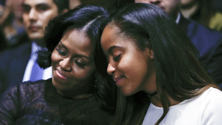 First lady Michelle Obama and daughter Malia lean into one another