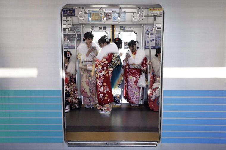 Image: Young Japanese women dressed in colorful kimonos use their smartphones on a train after attending a ceremony marking the Coming of Age Day at the Toshimaen Amusement Park, in Tokyo on Jan. 9.