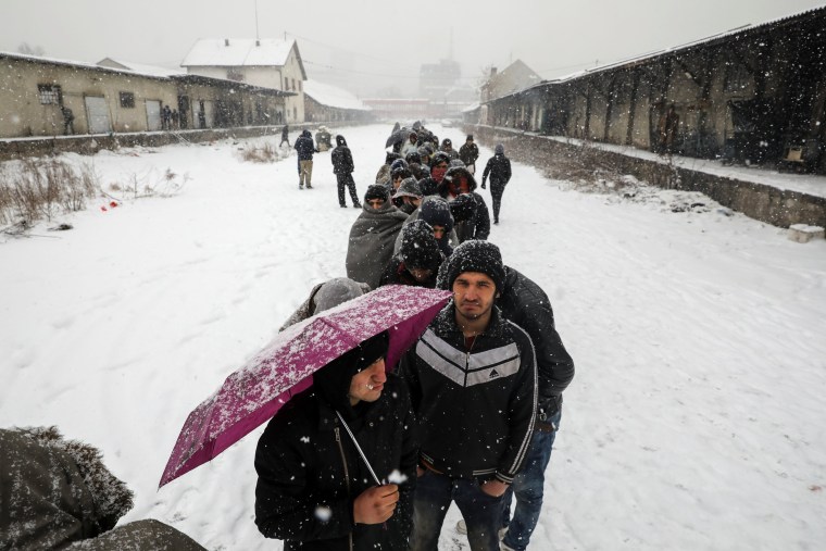 Image: Migrants wait in line to receive food outside a derelict customs warehouse in Belgrade, Serbia.