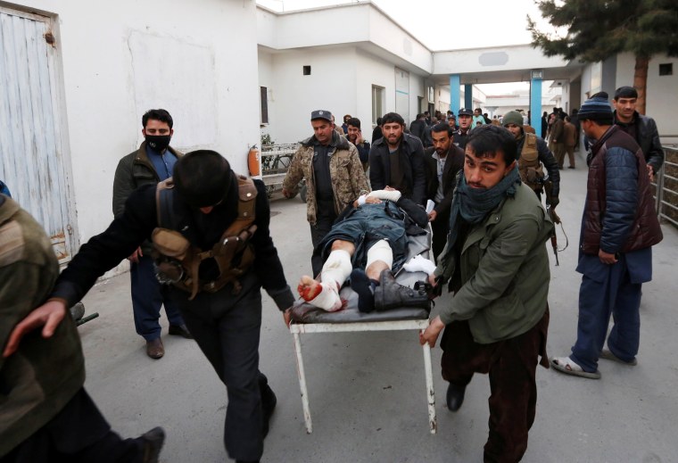Image: Men carry an injured police officer to a hospital after a suicide attack in Kabul
