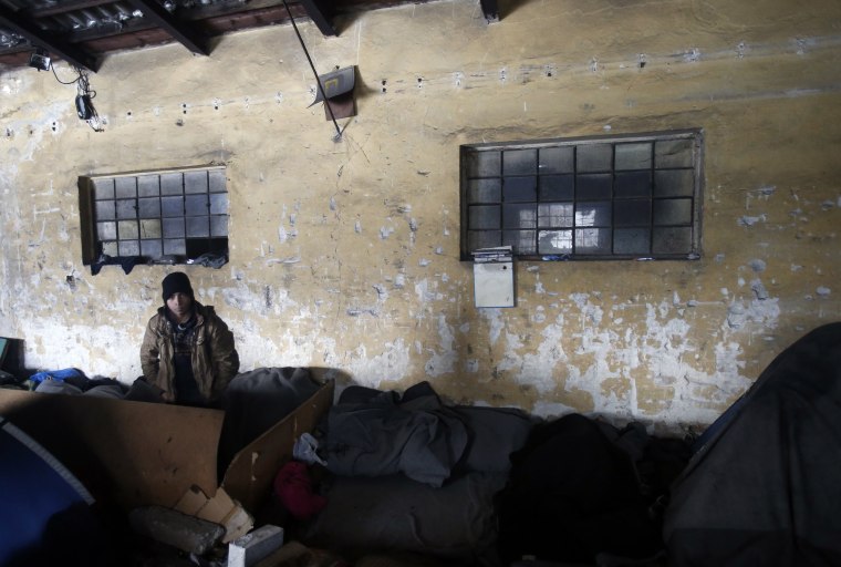 Image: A migrant walks through an abandoned warehouse in Belgrade