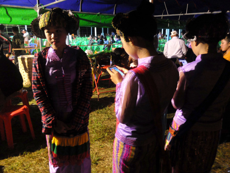 Image: Teenagers in traditional dress use their smartphones in Myanmar