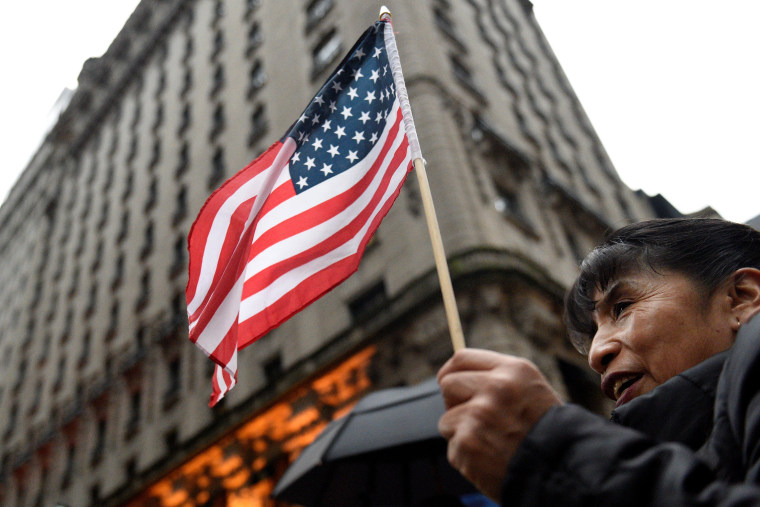 Image: A women holds an American flag while protesting outside Trump Tower during a demonstration organized by the New York Immigration Coalition against President-elect Donald Trump in the Manhattan borough of  New York