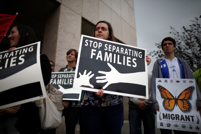 People hold signs at a protest against plans to deport Central American asylum seekers in Los Angeles