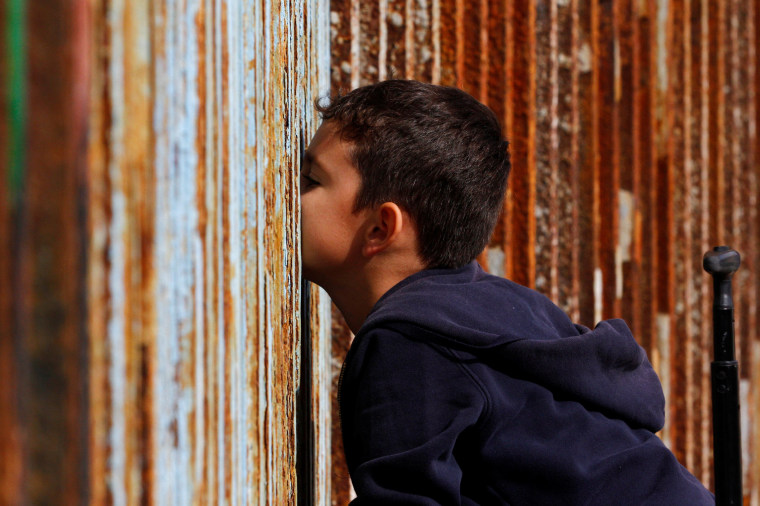 Image: A boy talks to his relatives across a fence separating Mexico and the United States, in Tijuana