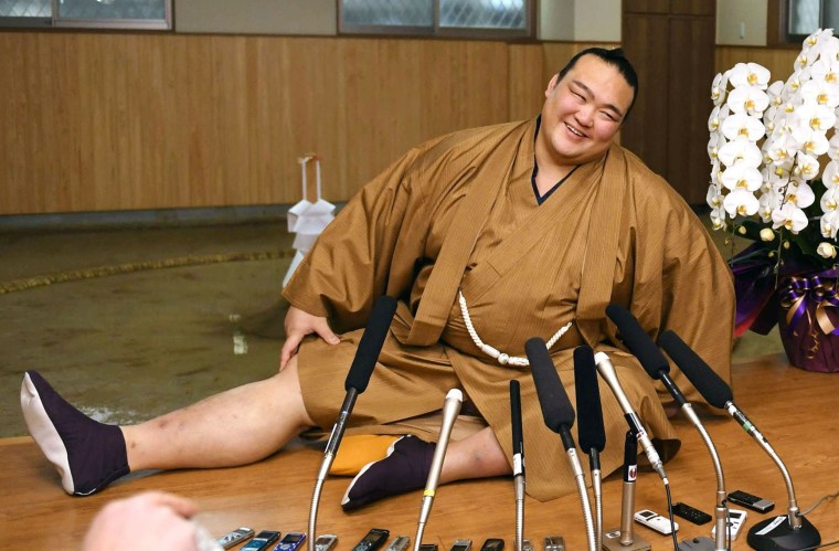 Image: New Year Grand Sumo Tournament winner ozeki Kisenosato stretches his legs during a press conference at his Tagonoura stable in Tokyo