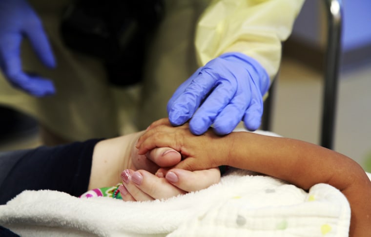 Image: A doctor uses a gloved hand to touch the hands of a woman and her daughter at All Children's Hospital in St. Petersburg, Florida on Sept. 18, 2015.