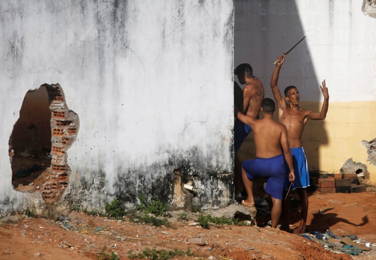 Image: An inmate gestures after riot policemen did a head count of them during an uprising at Alcacuz prison in Natal