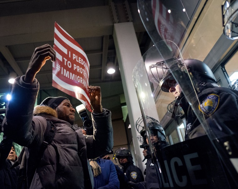 Image: A protester stands facing police officers at an entrance of Terminal 4 at John F. Kennedy International Airport in New York on Jan. 28 after earlier in the day two Iraqi refugees were detained while trying to enter the country.