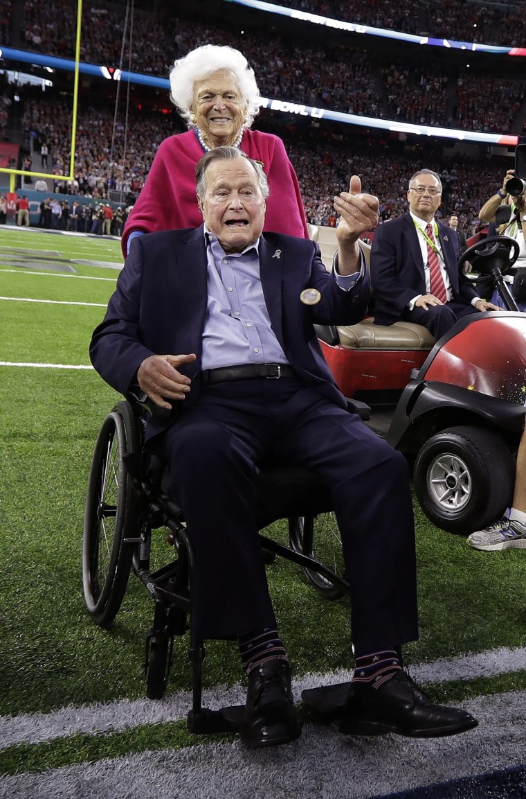 Former President George H.W. Bush tosses the coin as his wife, Barbara, watches before the NFL Super Bowl 51