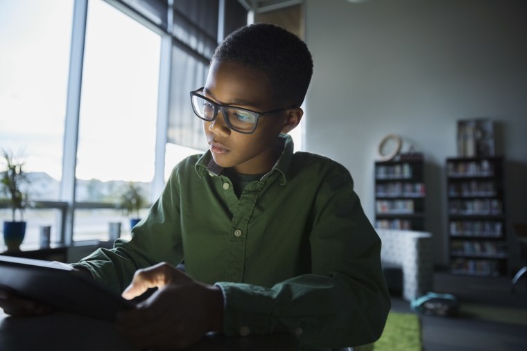 Elementary student using digital tablet in dark library