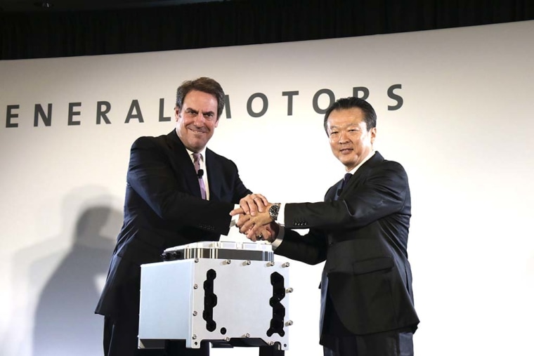 Mark Reuss, GM Global Product Development Chief, and Toshiaki Nikishiba, President and CEO of Honda North America, shake hands by a fuel-cell stack.