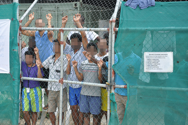 Asylum-seekers look through a fence at the Manus Island detention centre in Papua New Guinea