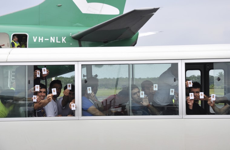 Image: A group of asylum seekers hold up their identity after landing in Manus Island, Papua New Guinea