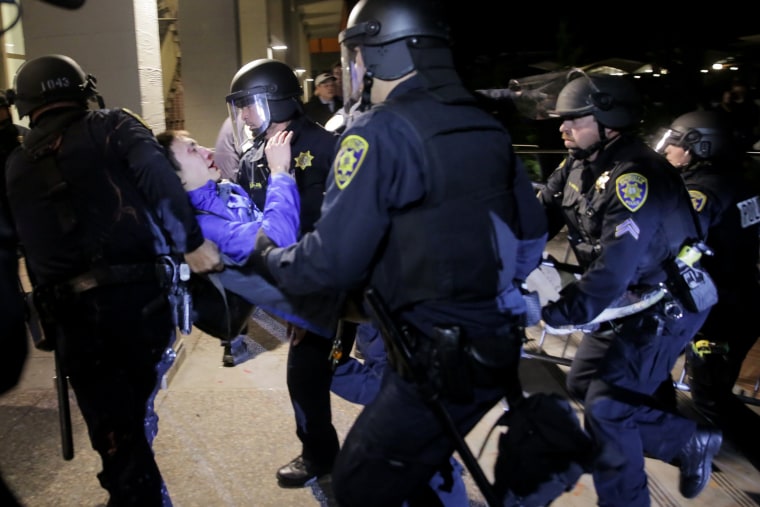 Image: A protester is carried into a building by police officers during a protest on the UC Berkeley campus