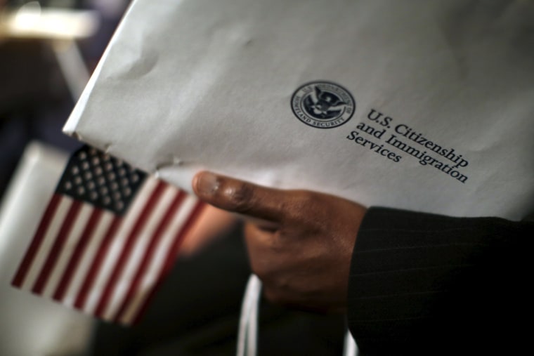 Image: A man holds an envelope from the U.S. Citizenship and Immigrations Service during a naturalization ceremony at the National Archives Museum in Washington