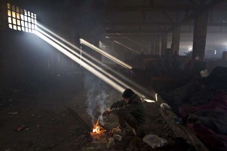 Image: An Afghan refugee warms himself by a fire in an abandoned warehouse in Belgrade, Serbia on Jan. 30.