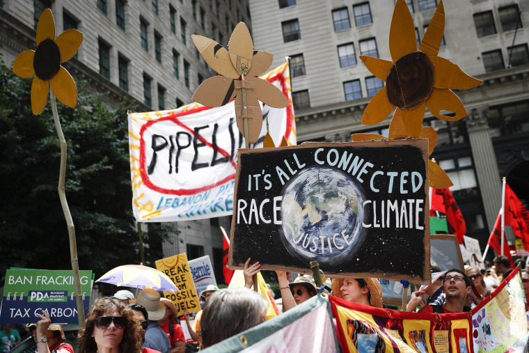 Image: Climate change activists carry signs as they march during a protest in downtown in Philadelphia a day before the start of the Democratic National Convention on July 24, 2016.