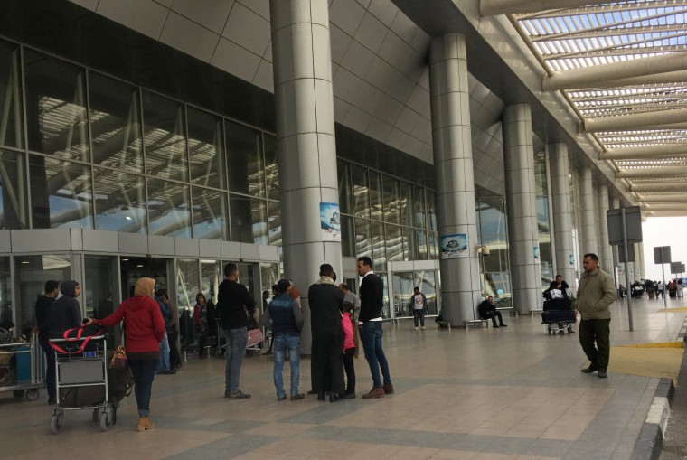Image: People wait outside a Cairo airport terminal