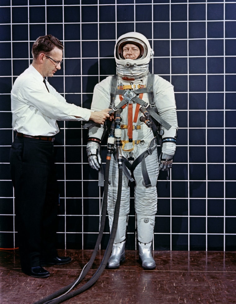 Engineer Bill Peterson fits test pilot Bob Smyth in an Apollo space suit with a Lunar Excursion Module restraint harness during suit testing in 1968.
