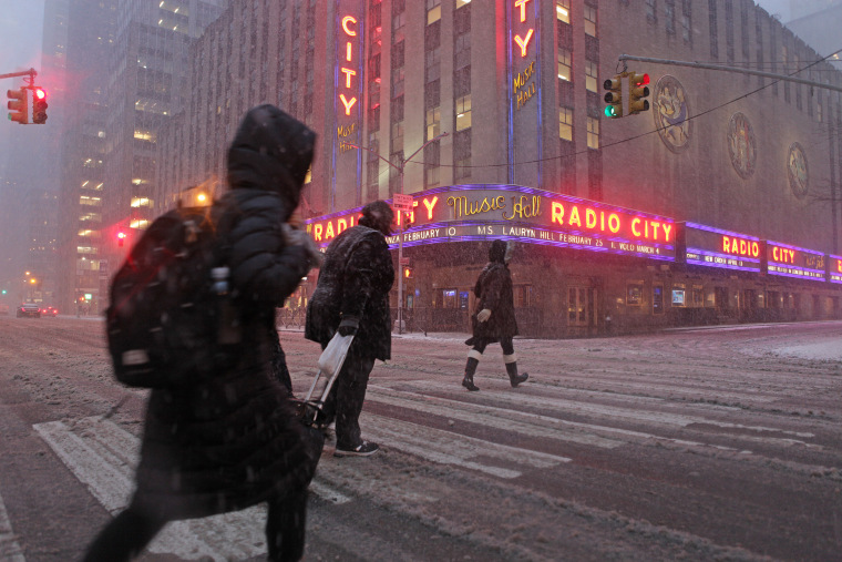 Image: Pedestrians walk through blowing snow in front of Radio City Music Hall