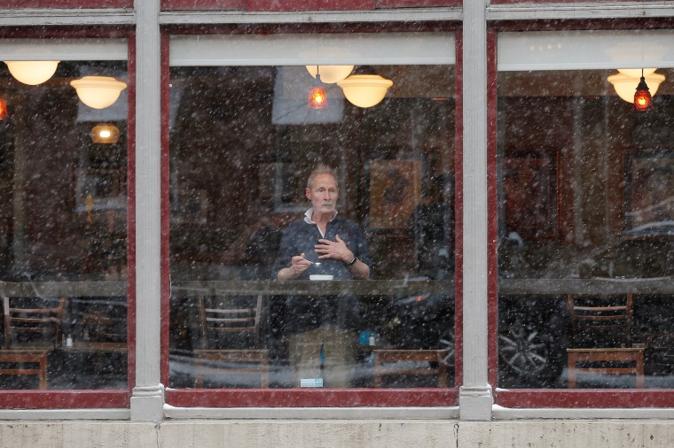 Image: A man looks out from a cafe's window during a winter nor'easter snow storm in Boston
